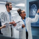 Healthcare professionals analyzing real-time clinical data on a high-tech digital monitor for QMSR compliance.