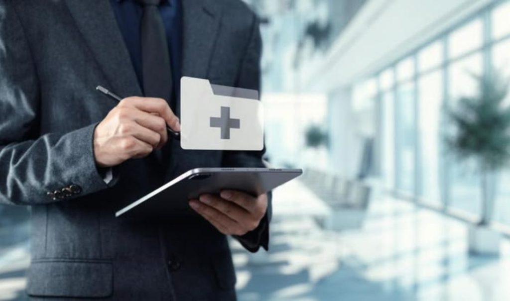A professional in a suit using a tablet with a digital medical folder icon. This represents a modern FDA inspector or quality manager conducting a digital GMP audit in a clean, corporate facility.