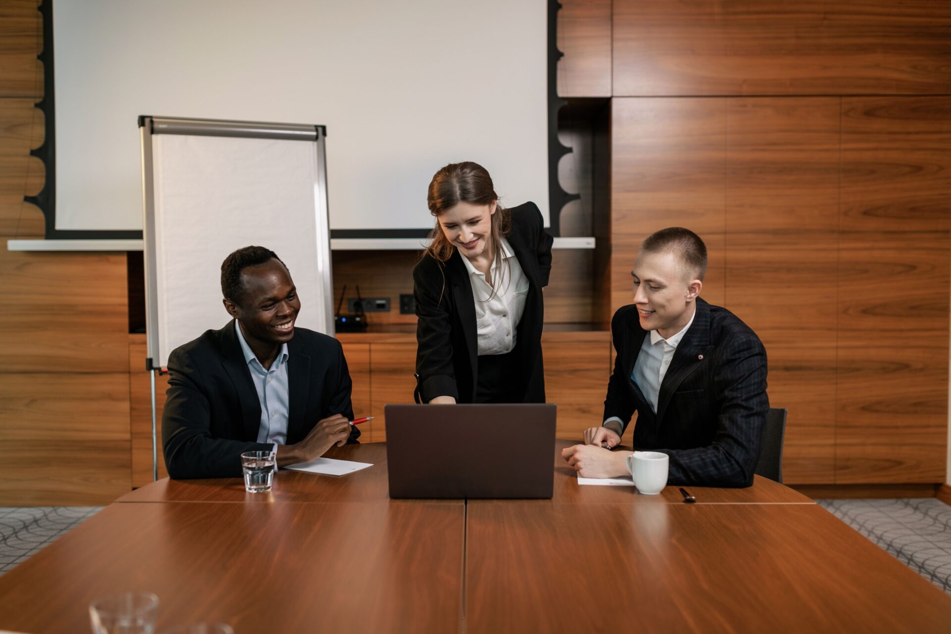 Three business professionals reviewing a laptop in a conference room